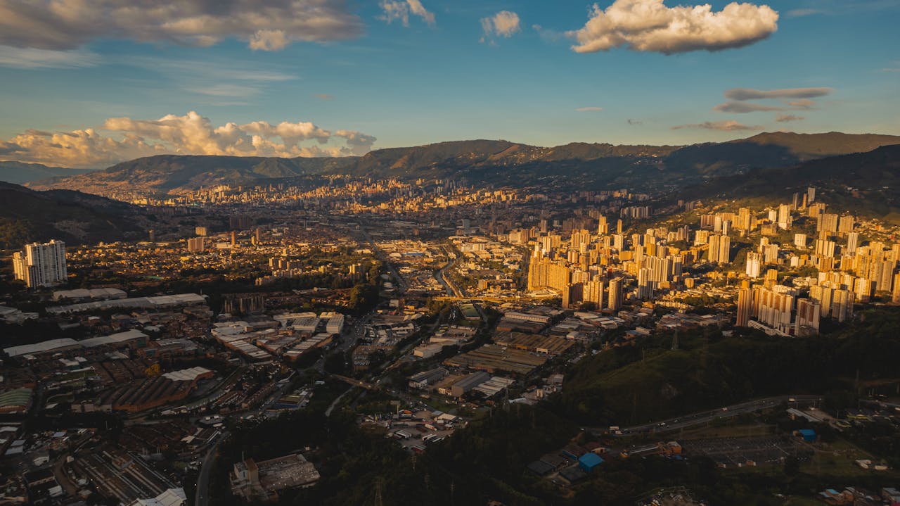 Stunning aerial view of Medellín's urban skyline surrounded by mountains at sunset.