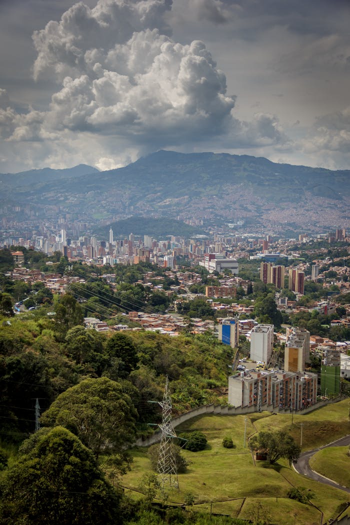 Stunning aerial view of Medellin cityscape under dramatic clouds and lush mountain backdrop.