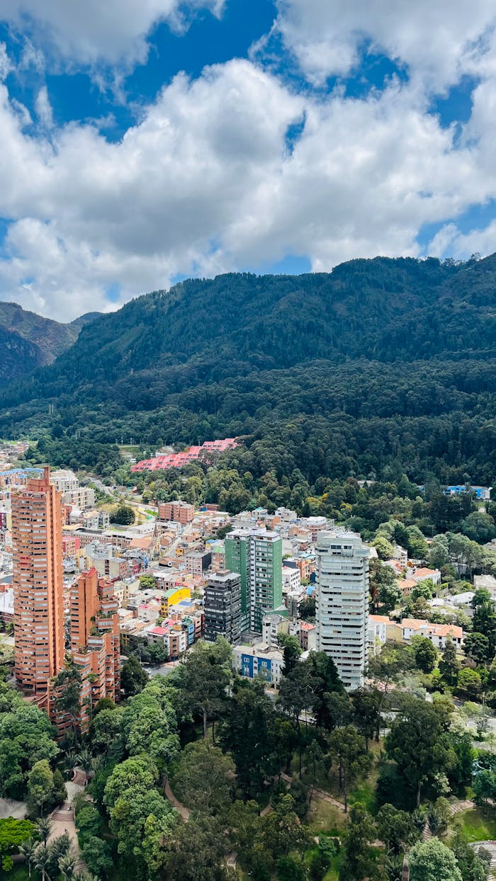 Discover a cityscape amidst lush greenery and towering mountains, showcasing urban architecture.