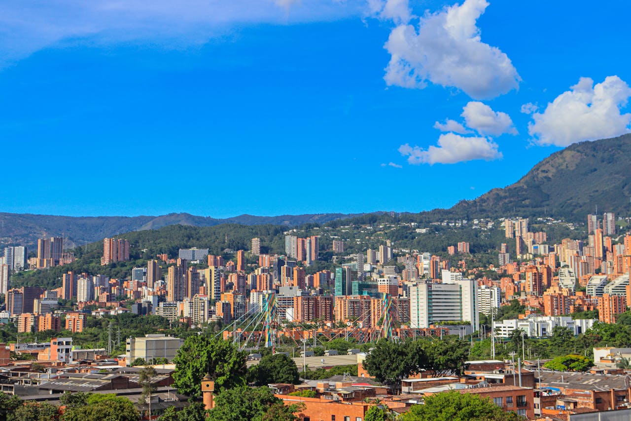 A stunning view of Medellín, Colombia with a backdrop of mountains and clear blue skies.